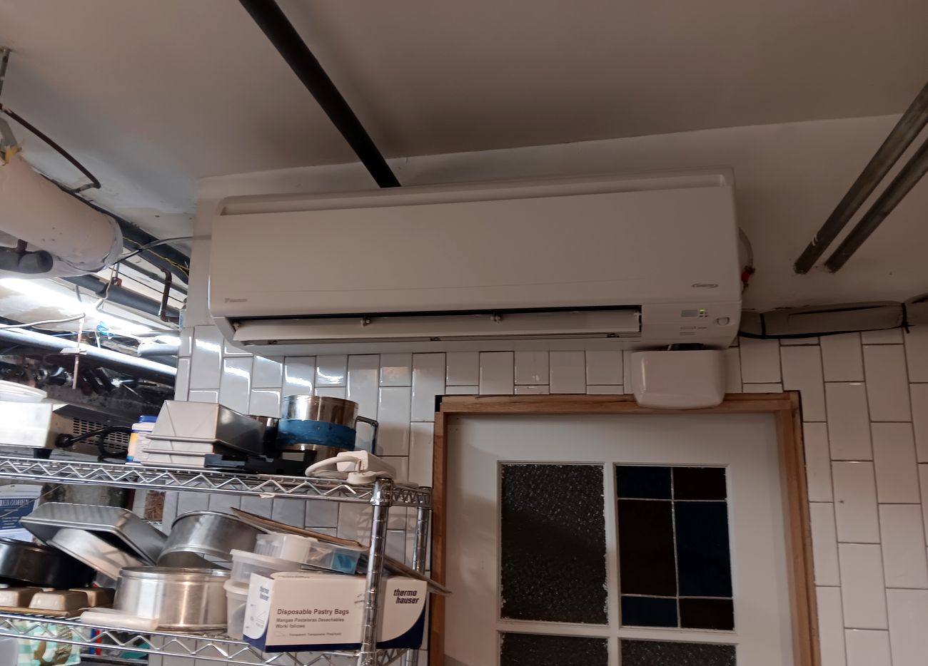 A ductless mini split head mounted high on the wall of a commercial kitchen