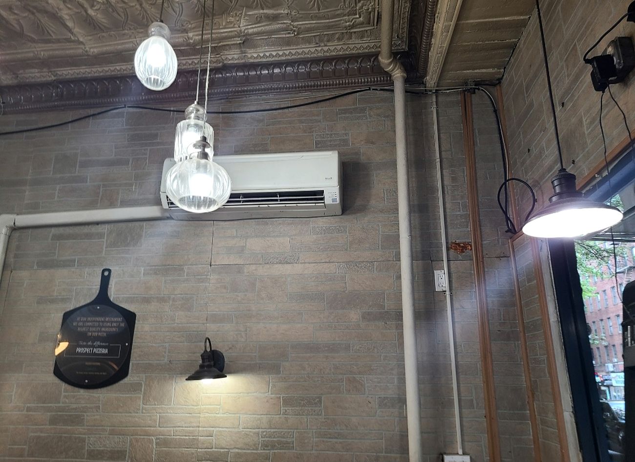 A ductless mini split head above the counter of a pizzeria